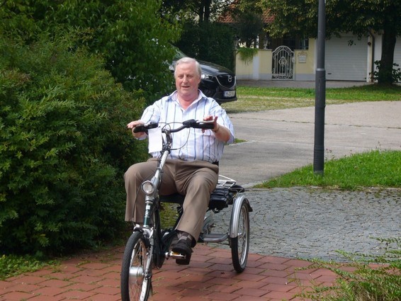 älterer Herr auf einem Dreirad in der Stadt