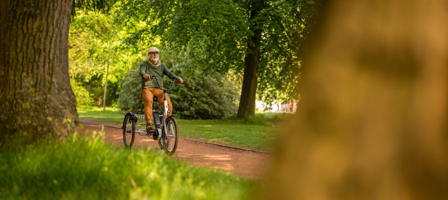 Mann fährt mit Dreirad durch den Wald